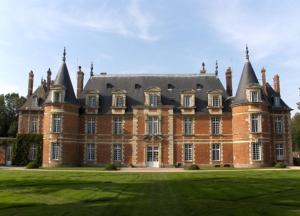 a large brick building with a grass field in front of it at Château de Miromesnil in Tourville-sur-Arques