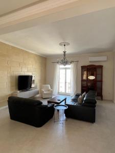 a living room with a black couch and a tv at Spacious & Central 3-Bedroom Apartment Close to the Sea in Taʼ Xbiex +26 photos