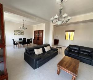 a living room with a black leather couch and a table at Spacious & Central 3-Bedroom Apartment Close to the Sea in Taʼ Xbiex