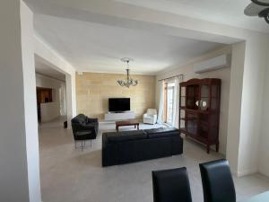 a living room with a black couch and chairs at Spacious & Central 3-Bedroom Apartment Close to the Sea in Taʼ Xbiex