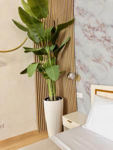 a white vase with a plant in a bedroom at Onny's Palace in Bari