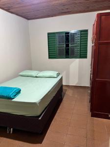 a bed in a room with a green window at Casa central in Dourados