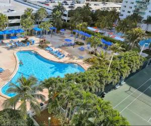 an overhead view of a pool with palm trees and blue umbrellas at Apartments Miami in Sunny Isles Beach