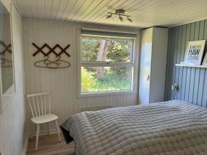 a bedroom with a bed and a window and a chair at VE160-Vejers-Strand-Engesovej-69 in Vejers Strand
