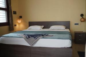 a bedroom with a large bed with a blanket on it at Nirvana Yogashala Retreat in Mysore