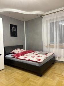 a bedroom with a bed with a red and white comforter at Rooms near Balice airport in Cholerzyn
