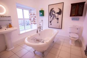 a bathroom with a tub and a horse picture on the wall at Rooms At Greystoke in Criccieth