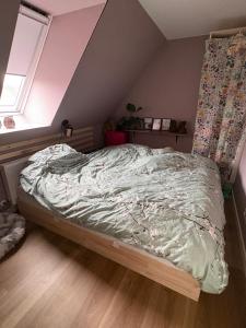 an unmade bed in a room with a window at Rolig base under smukfest in Skanderborg