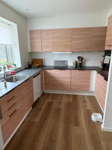 a kitchen with wooden cabinets and a wooden floor at Rolig base under smukfest in Skanderborg
