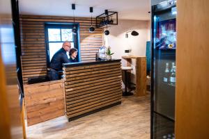 two people standing at a bar in a restaurant at Pension Linder in Seeboden