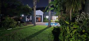 a backyard of a house with a swimming pool at night at Maison Akiba in Pretoria