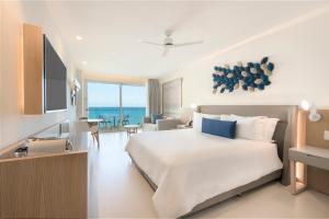 a bedroom with a large bed and a living room at Royalton Splash Riviera Cancun, An Autograph Collection All-Inclusive Resort in Cancún