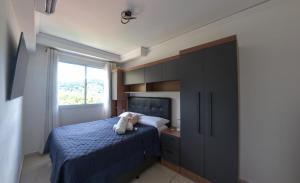 a bedroom with a blue bed and a window at Apartamento luxo, há 5min do centro de Itaipava in Petrópolis +30 photos