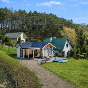 a white house with a green roof and a yard at Slow Lake House Koszarka in Gródek Nad Dunajcem