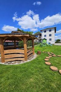 a wooden gazebo in a park with a playground at Apartamenty Welskie in Lidzbark