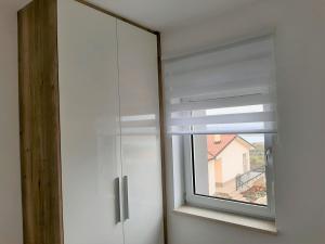 a white cabinet with a window with a window shade at Apartma Dana in Jadranovo