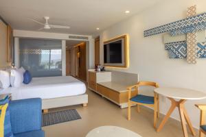 a bedroom with a bed and a desk and a table at Royalton Splash Riviera Cancun, An Autograph Collection All-Inclusive Resort in Cancún