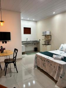 a bedroom with a bed and a table and a kitchen at Chalés Flor de Mandacaru in Monte das Gameleiras