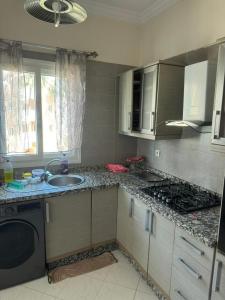 a kitchen with a sink and a stove at Résidence Al kawtar, Mimosa Appartement in Ben Slimane