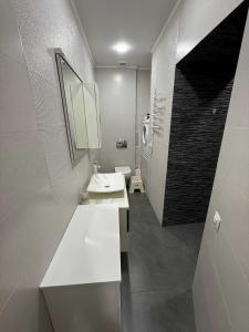 a white bathroom with a sink and a mirror at Chirons Rest in Volos