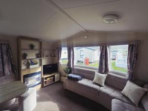 a living room with a couch and a window at Barmouth wave - Sunnysands Holiday Park caravan in Llanddwywe