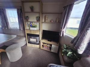 a living room with a tv and a living room with a table at Barmouth wave - Sunnysands Holiday Park caravan in Llanddwywe