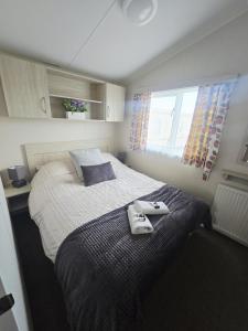 a bedroom with a large bed with towels on it at Barmouth wave - Sunnysands Holiday Park caravan in Llanddwywe +25 photos