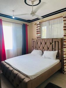 a bedroom with a large bed with white sheets at Honed homes in Mombasa