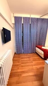ein Zimmer mit blauen Vorhängen, einem Bett und einem Fernseher in der Unterkunft Host Roma in Rom