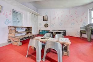 a room with a table and chairs in a room with a red floor at hotel O snow breeze adventures in Dhanaulti