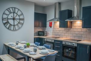 a kitchen with a table and a clock on the wall at The Shaftesbury House - 8 Bedroom House in Stockton-on-Tees