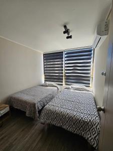 a bedroom with two beds and a window with a fan at Apartamento Los Andes II in Los Andes