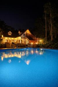 a large blue swimming pool in front of a house at night at Cloud Hills Munnar in Kallar Vattiyar
