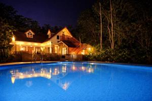 a large swimming pool in front of a house at night at Cloud Hills Munnar in Kallar Vattiyar +22 photos