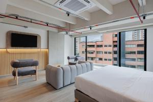 a bedroom with a bed and a tv and a chair at Lomm By Somos The Group in Medellín