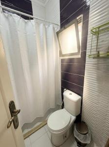 a bathroom with a white toilet and a window at CozyQ Apt in Aqaba