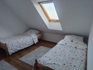 a small bedroom with two beds and a window at Ostoja Jaczno in Smolniki