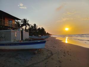 a boat sitting on the beach at sunset at Cabaña los recuerdos de ella in Moñitos