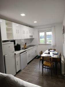 a kitchen with white cabinets and a table and a dining room at La ERA in Aldeadávila de la Ribera