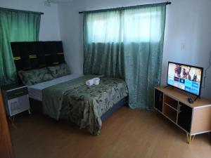 a small bedroom with a bed and a television at Tatami Guesthouse in Parow