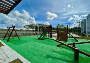 a playground with green grass and a swing at Conforto103 in Caruaru