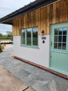 a house with a green door and a patio at The Old Barn in Hanbury