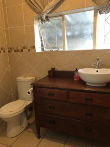 a bathroom with a toilet and a sink and a window at Knowles Nook Self-catering in Klerksdorp