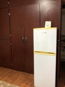 a white refrigerator in a kitchen with wooden cabinets at Knowles Nook Self-catering in Klerksdorp