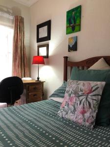 a bedroom with a bed and a desk with a lamp at Knowles Nook Self-catering in Klerksdorp