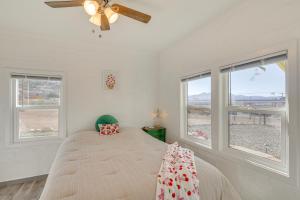 a bedroom with a bed with a ceiling fan and windows at Route 66 Roadtripper Retreat w/ Private Backyard in Kingman