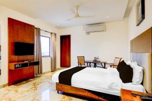 a bedroom with a bed and a tv and a table at Townhouse JFN Comfort Hotel in Chennai
