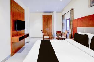 a bedroom with a bed and a tv and chairs at Townhouse JFN Comfort Hotel in Chennai +23 photos