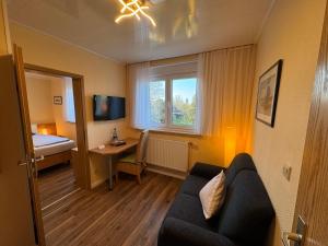 a room with a couch and a bed and a window at Hotel Zum Hanseaten in Borkum