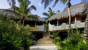 an old house with a thatched roof and stairs at Zamas Hotel in Tulum